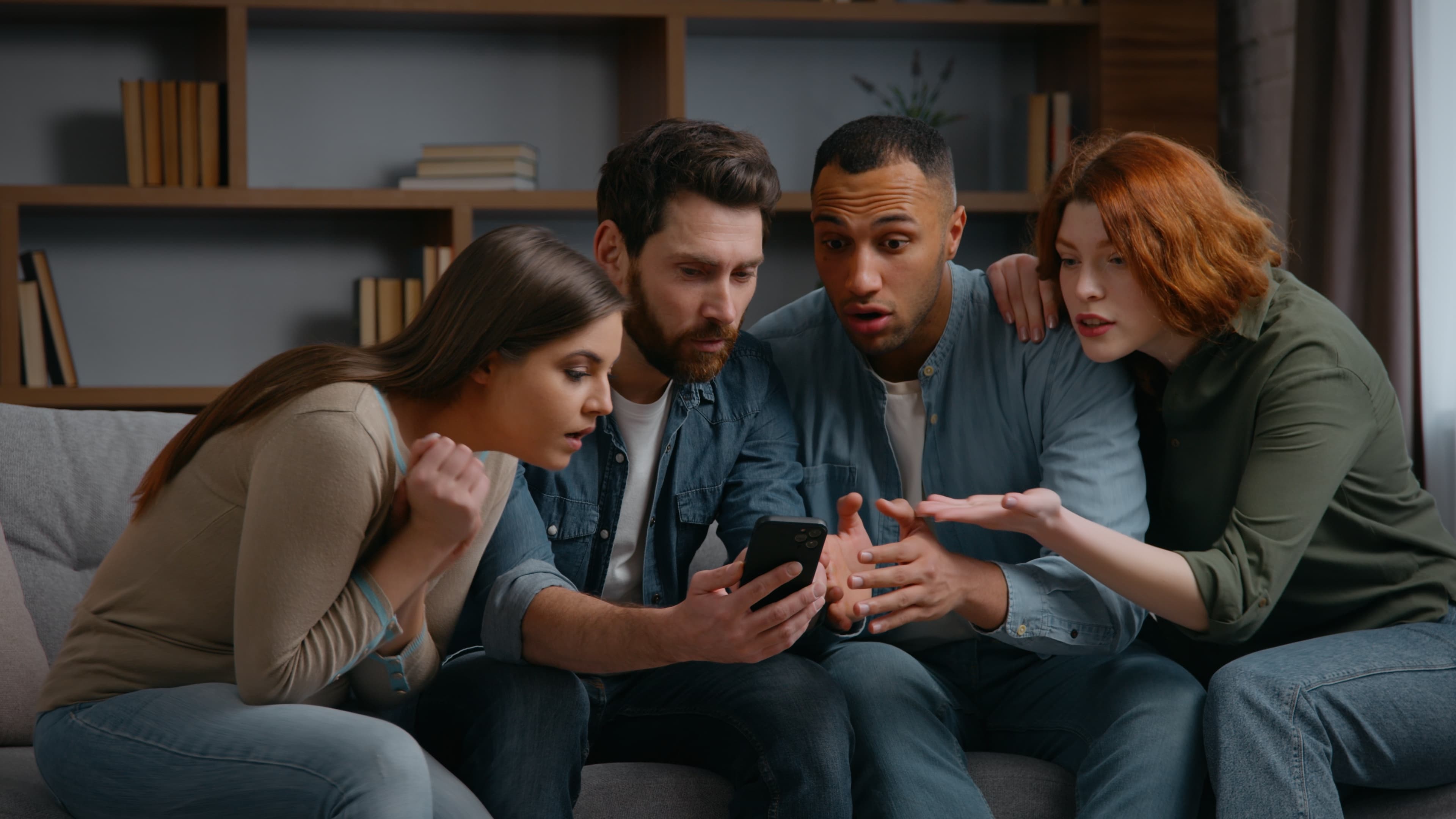 Three people huddled around a phone watching a video