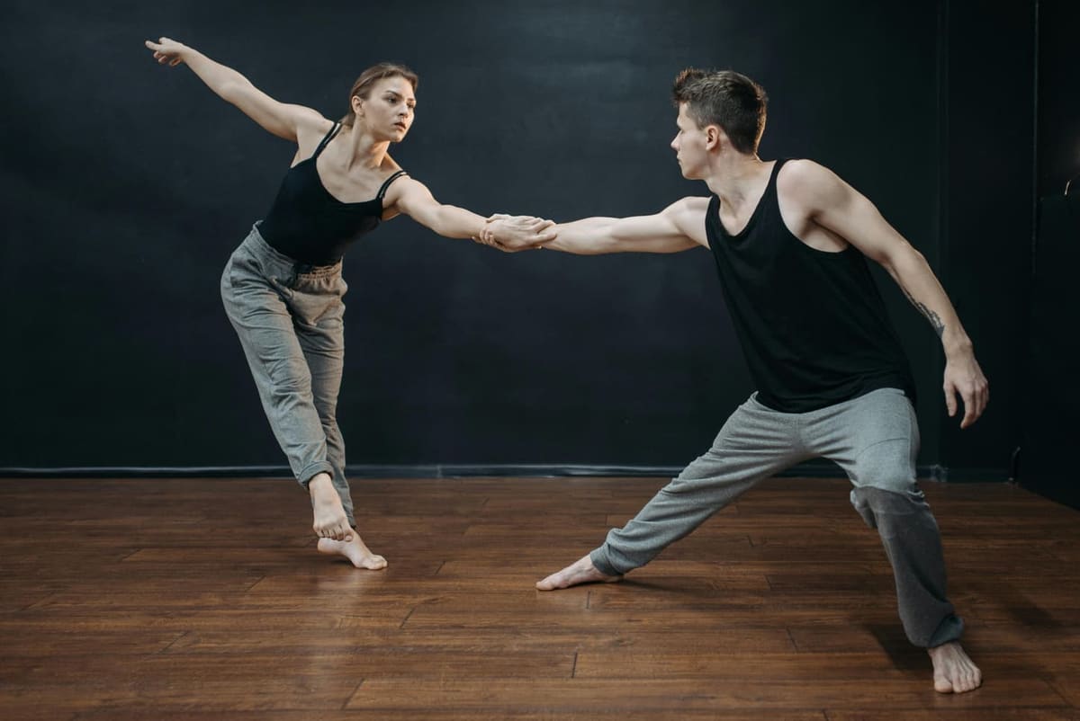 Two dancers in motion on a dim stage