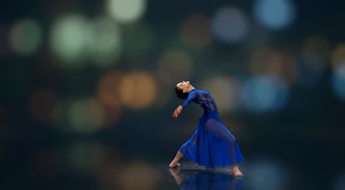 A dancer in a blue dress arched backward