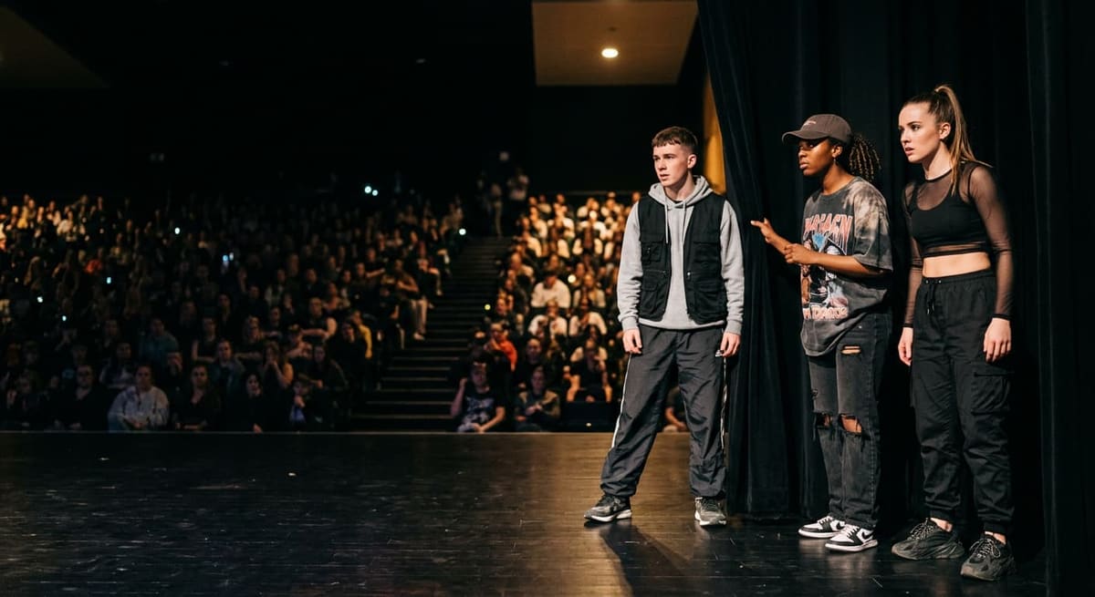 Three young performers standing on stage in front of an audience